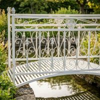 The Westminster Victorian Ornate Wrought Iron Garden Bridge in a White Finish Shown in a Sunny Private Garden over a Small Stream Focussing on the Left Side - Digital Illustration The Westminster Victorian Ornate Wrought Iron Garden Bridge in a White Finish Shown in a Sunny Private Garden over a Small Stream Focussing on the Left Side - Digital Illustration