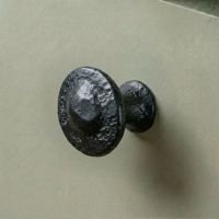 Traditional Black Iron Button Design Cabinet or Cupboard Knob Mounted on a Green Kitchen Cupboard Door - Digital Illustration 