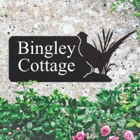 Pheasant Iron House Name Sign on a Stone Wall