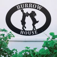 Boxing Hares Iron Oval House Sign on a White Wall