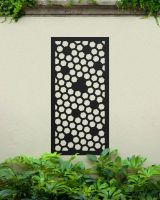 Black "Honeycomb Pattern Wall Art" on a cream coloured garden wall behind garden plants