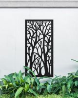 "Black Autumnal Trees Garden Wall Screen" mounted onto a white garden wall amongst plants