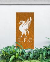 Rustic "Liver Bird Wall Art" mounted on a white garden wall behind garden plants 