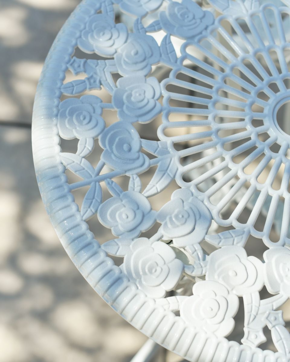 Close up of intricate table top detail on white patio two seater table and chairs set