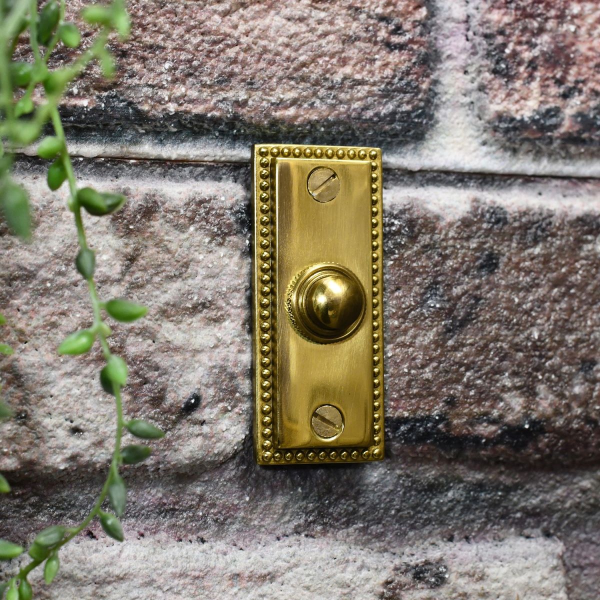 Solid brass door buzzer on brick wall