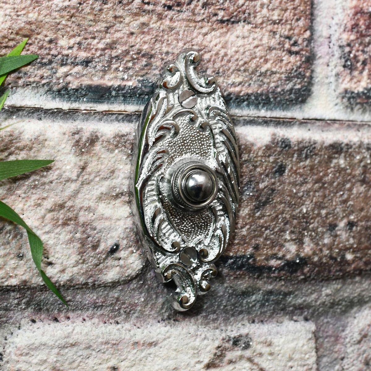 Bright chrome door bell on brick wall