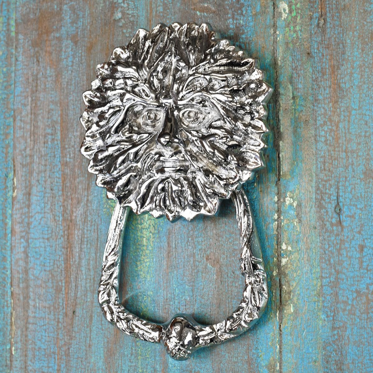 bright Chrome Green Man door knocker on rustic door