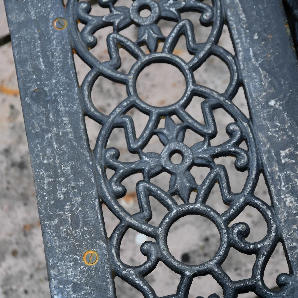 Close up of decorative seat on Aged Black Cast Iron Bench