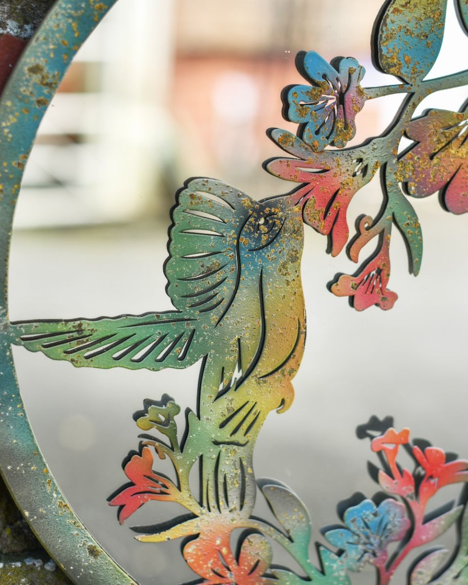 Close up of colourful rustic hummingbird detail on garden wall art