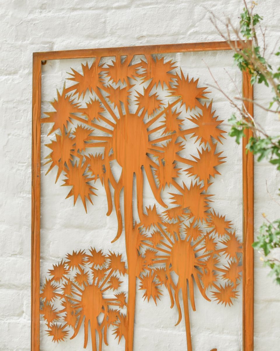Close up of intricate dandelion cut out detail on rustic garden wall art