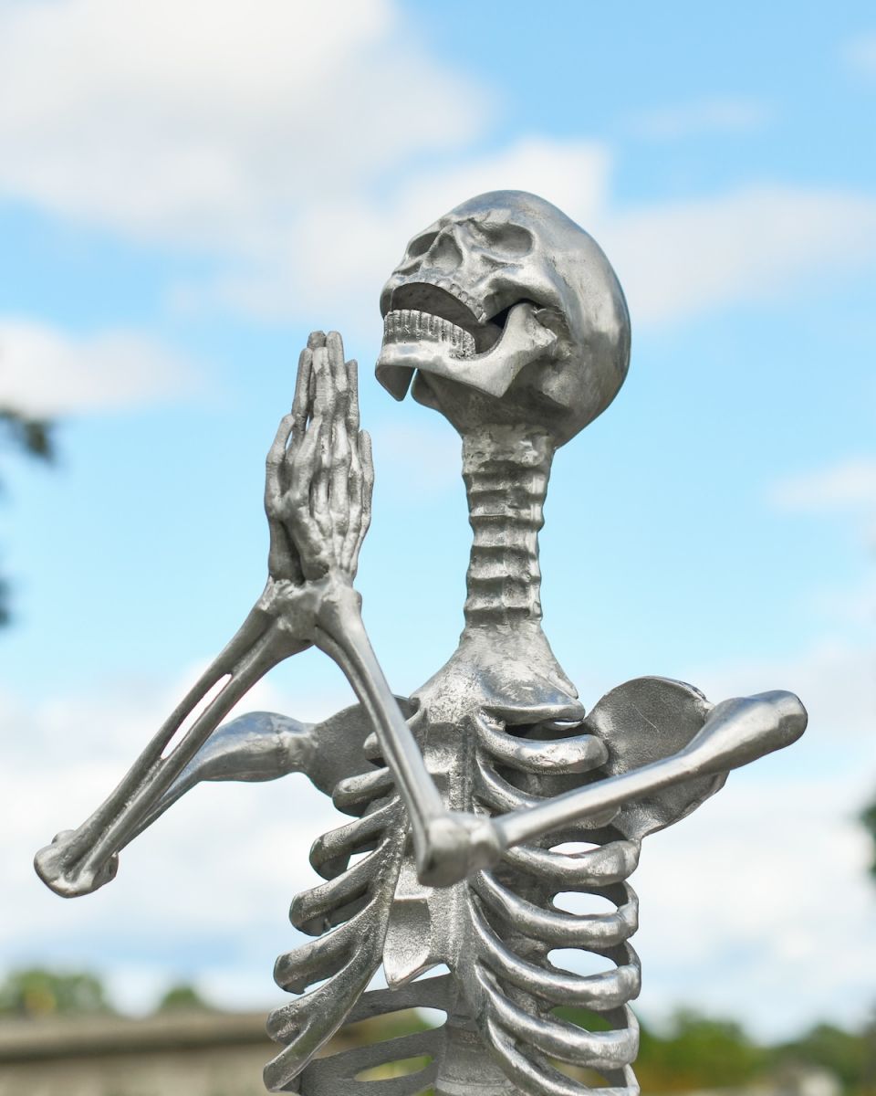 Close up of intricate face and hands detail on skeleton garden statue