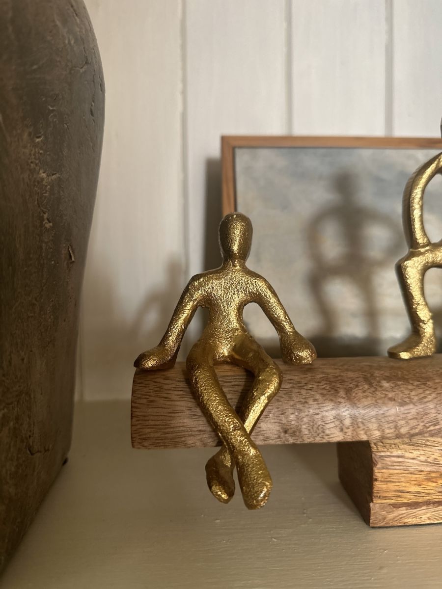 Close up of gold figure on aluminium and mango wood sculpture