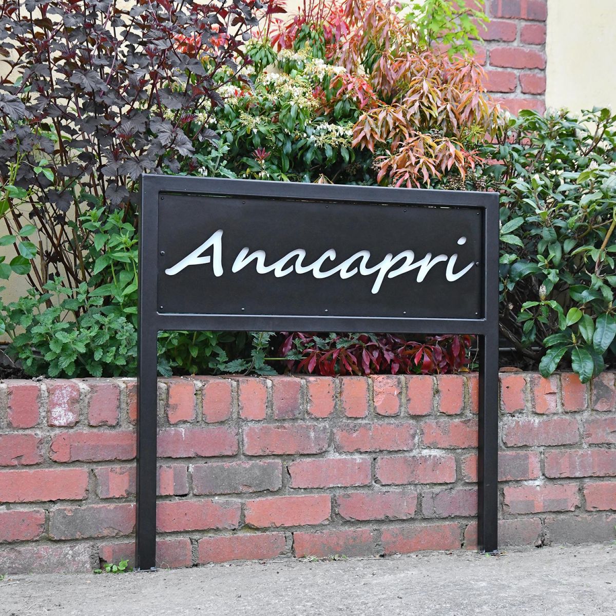 Black Iron Standing House Name Sign Next to a House