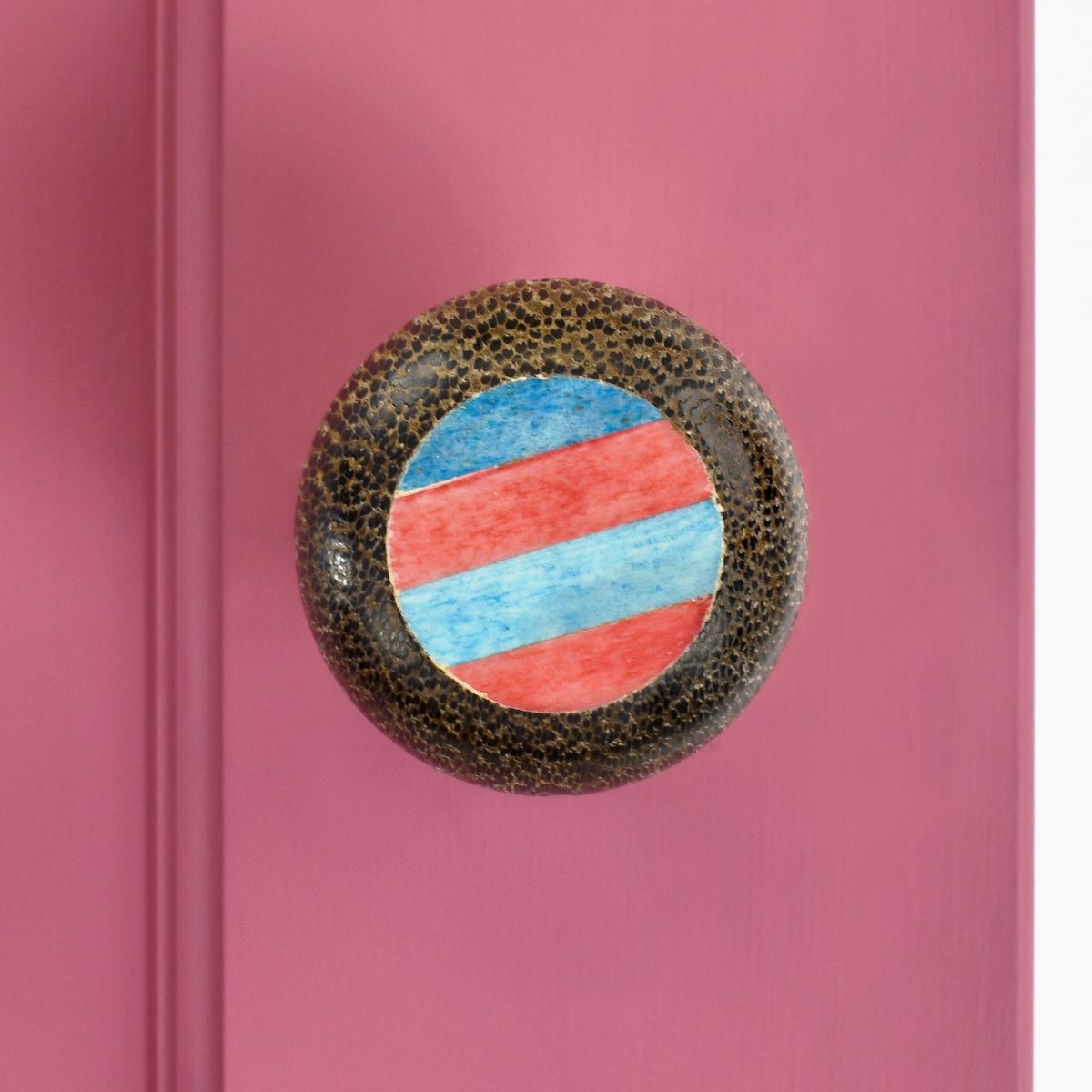 Unique Blue and red door knob on a pink door