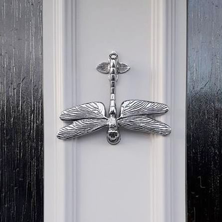 Bright chrome Dragon fly door knocker on white door
