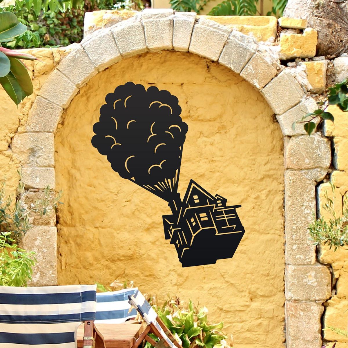 Floating House on Balloons Steel Wall Art on a Yellow Brick Wall in a Garden