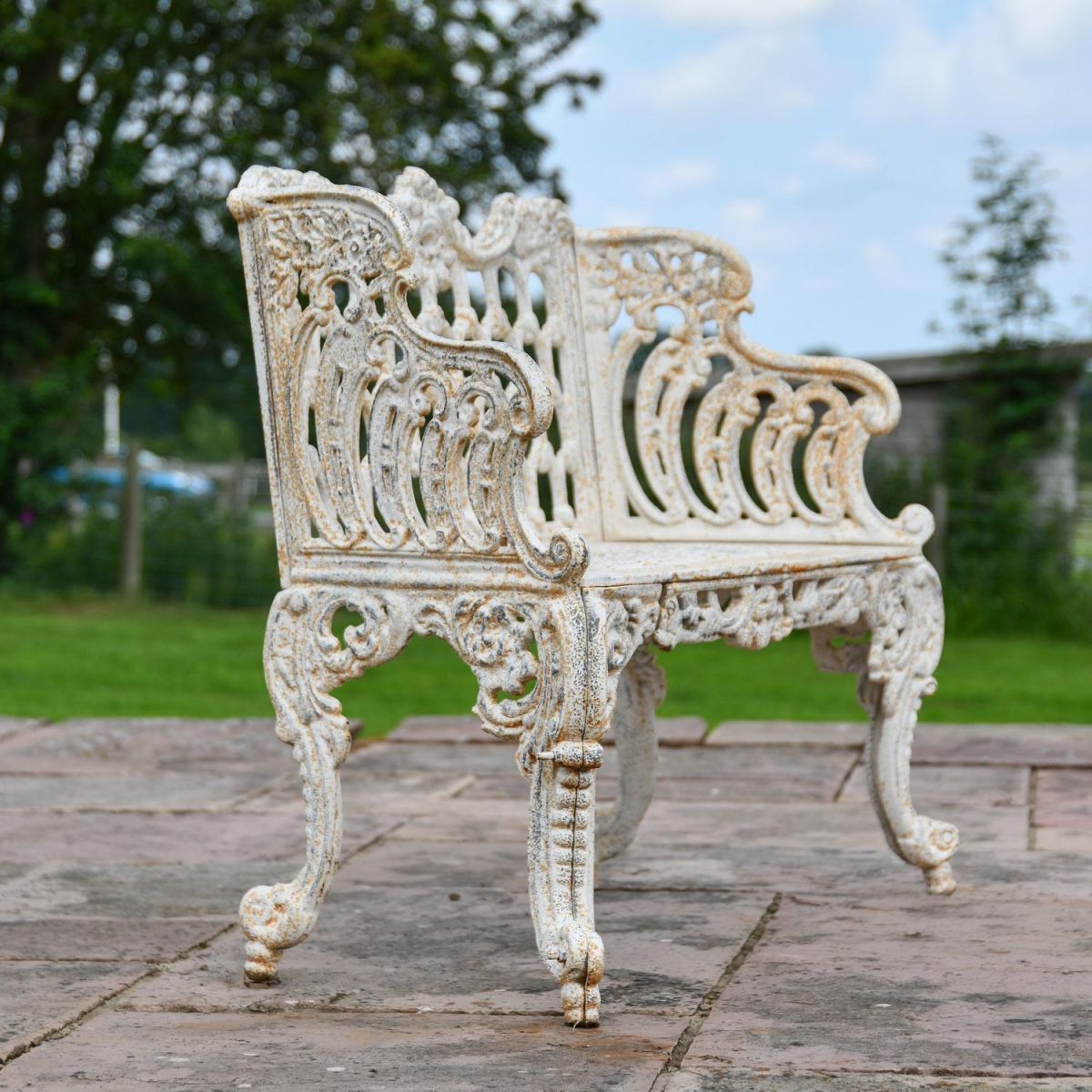 Side view of Ornate Cast Iron Antique Cream Garden Bench in Situ