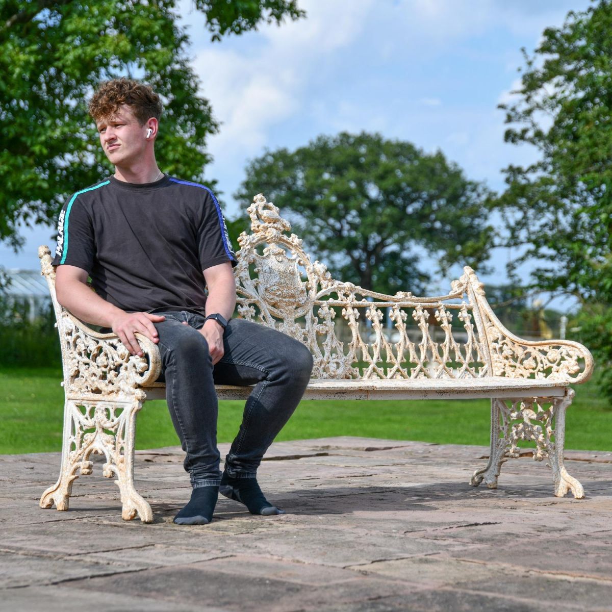 Male sat on Three Seater Antique Cream Garden Bench for Scale