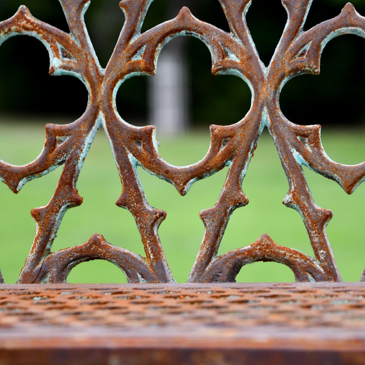 Close up of decorative design on backrest of rustic cast iron garden bench