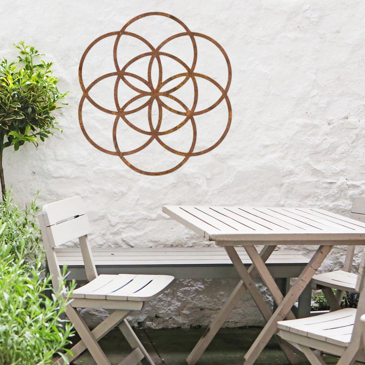 Rustic "Seed of Life" Steel Wall Art in Situ Outdoors by a Wooden Table and Chairs Set