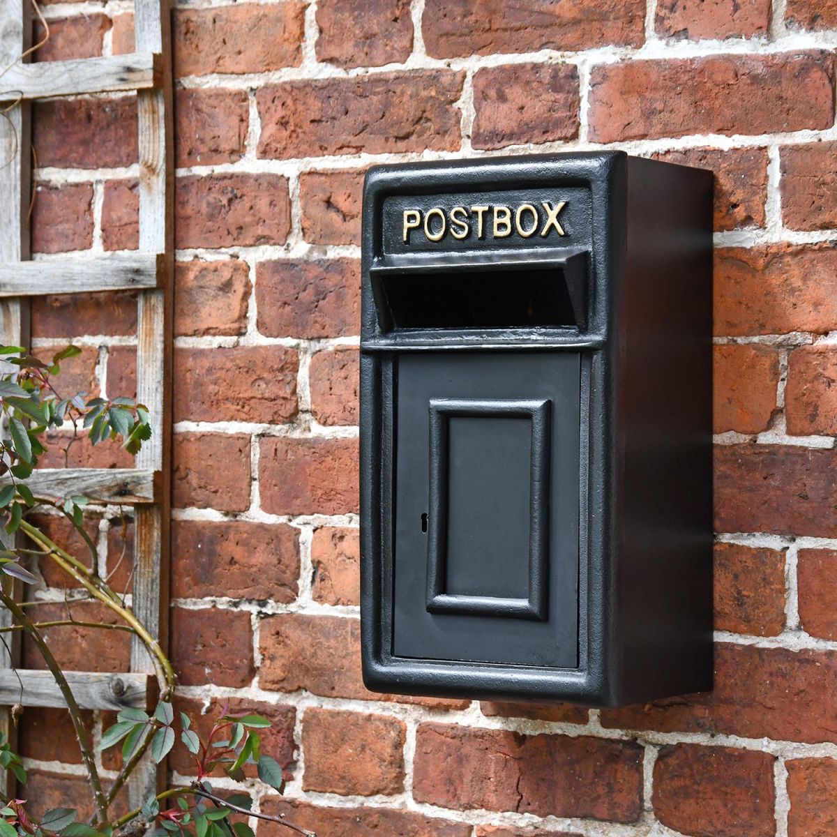 Traditional Black & Gold Wall Mounted Post Box Mounted on a Brick Wall
