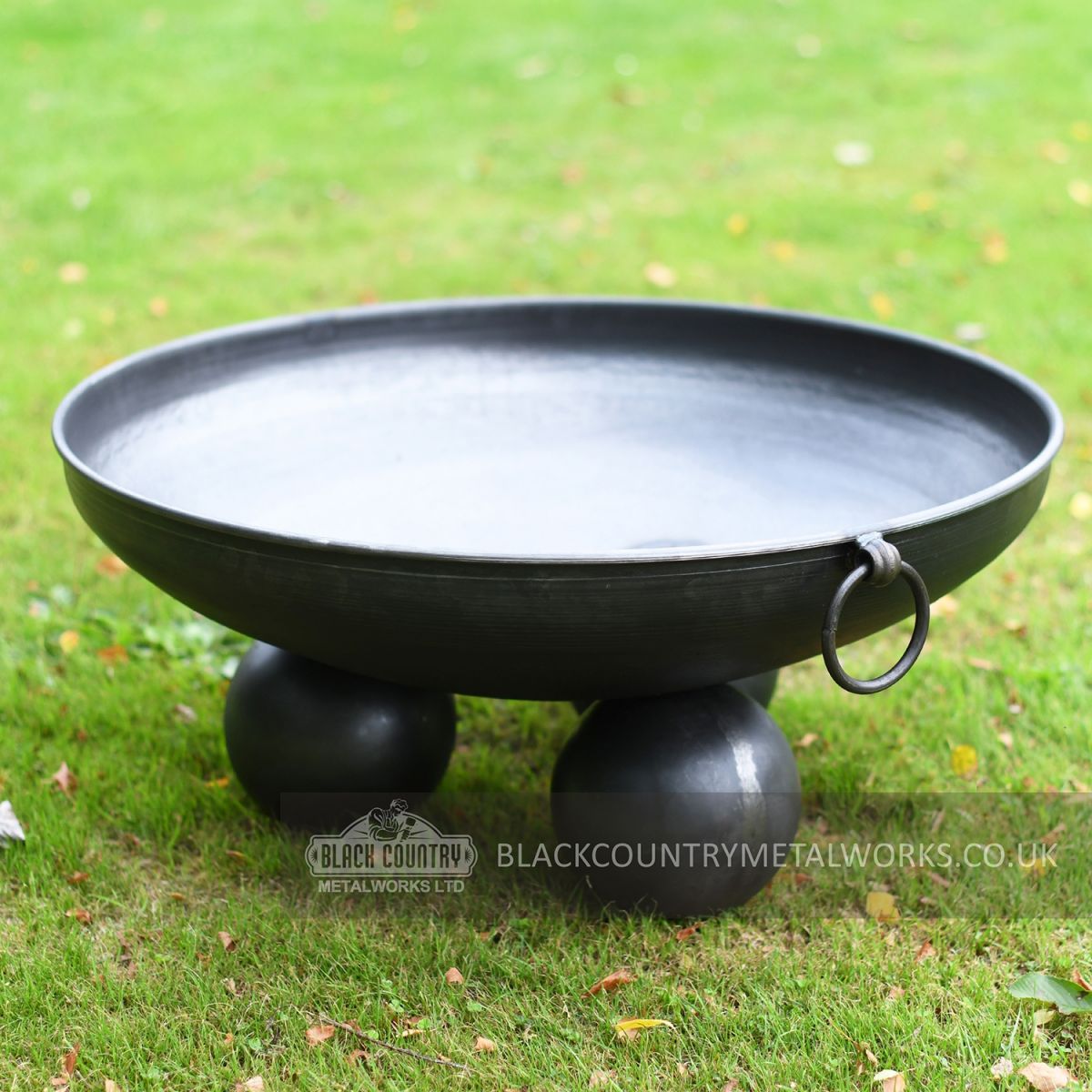 Black Fire Pit With Ball Feet on Lawn