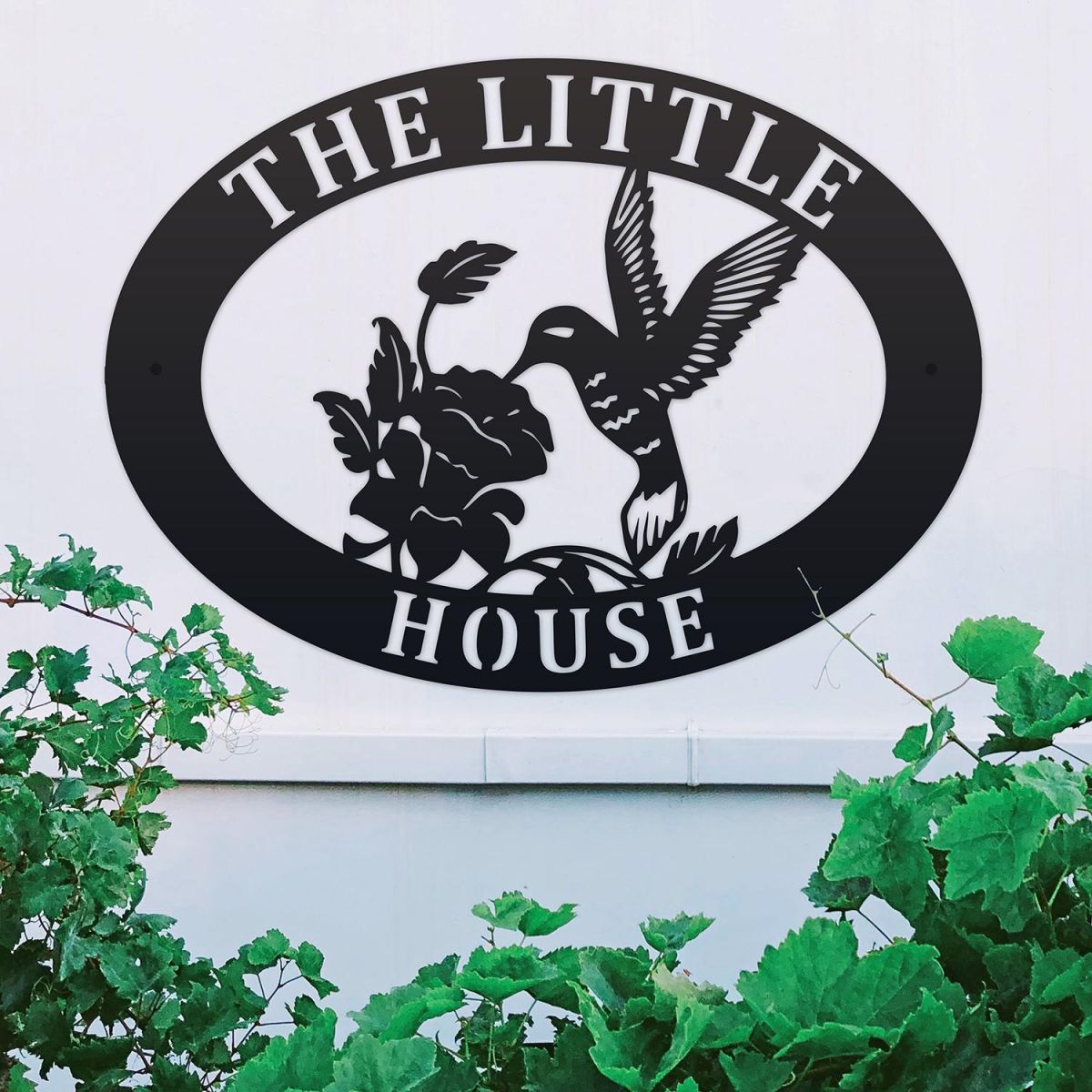 Hummingbird Iron Oval House Sign on a White Wall