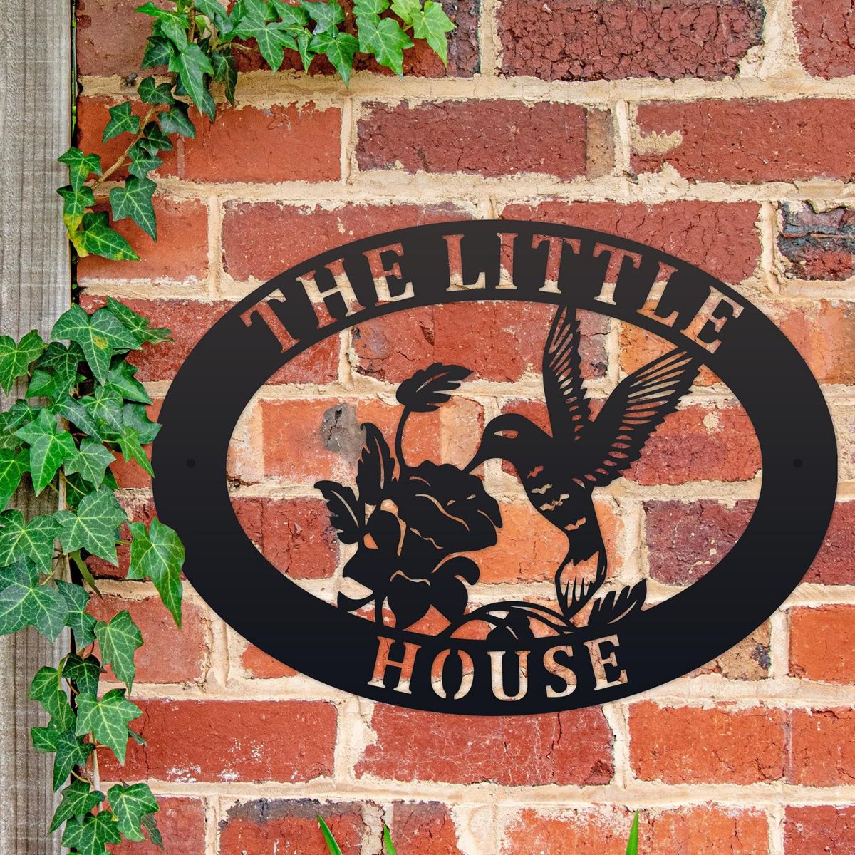 Hummingbird Iron Oval House Sign on a Brick Wall