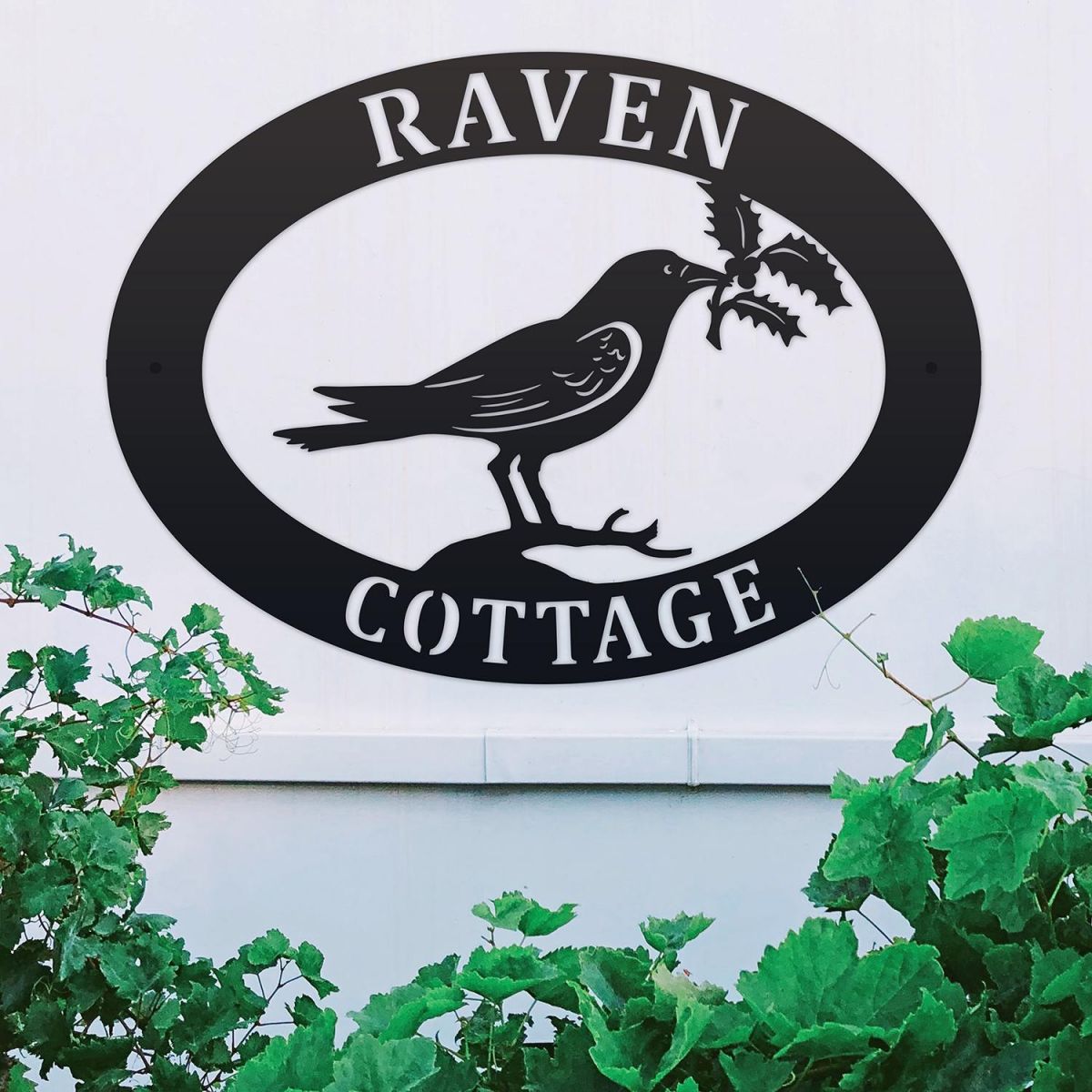 Raven & Holly Iron Oval House Sign on a White Wall