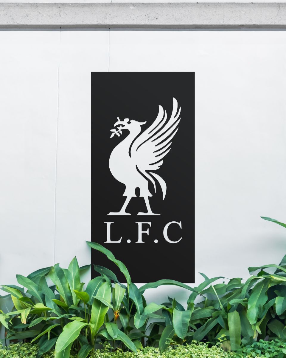 Black "Liver Bird Wall Art" on a white garden wall behind garden plants 