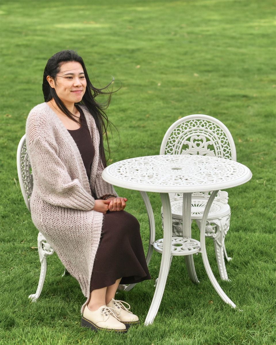 Woman Sitting at Cast Aluminium "Hamptons" White Two Seater Garden Table & Chair Set 