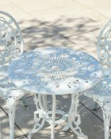 Close up of intricate table top detail with parasol hole on cast aluminium white bistro set