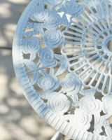 Close up of intricate table top detail on white patio two seater table and chairs set