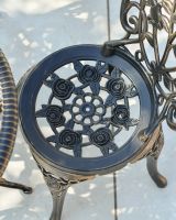 Close up of floral detailing on chair seat on ornate two seater bistro set
