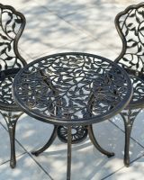 Close up of vine detailing on antique bronze two seater table and chairs furniture set