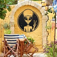 Peace Sign Alien Wall Art in Situ on a Yellow Garden Wall