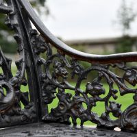 Side view of Aged Black Cast Iron Single Seat Bench