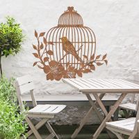 Bird Cage Wall Art in the Garden Above a Wooden Table & Chair Set