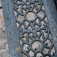 Close up of decorative seat on Aged Black Cast Iron Bench