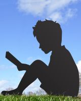 Boy With Book Silhouette sitting on grass with blue sky background 