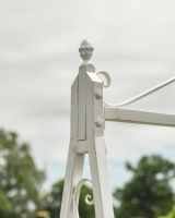 Close up of ornate detailing on champagne wrought iron garden swing bench