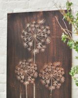Close up of intricate dandelion cut out detail on garden wall art