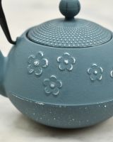 Close up of intricate floral detailing on light blue and silver japanese inspired teapot