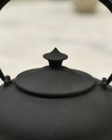 Close up of ornate lid detail on matte black teapot