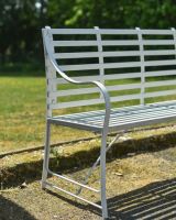 Close up of intricate curved arm detail on white garden bench