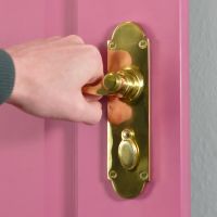 Polished Brass 6 Inch Lever Lock Handles on Pink Door in Use