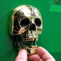 Scale image of polished brass skull door knocker
