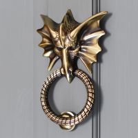 Brass dragon door knocker on grey door