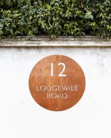 Modern Circular House Sign in Situ on a White Garden Wall