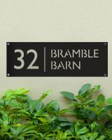Black Rectangular Steel House Number Sign Mounted onto a Green Painted Wall 